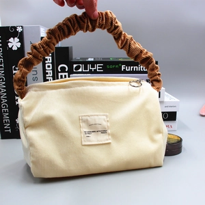 Detail of corduroy makeup bag with contrast scrunchie handle and secure metal zipper
