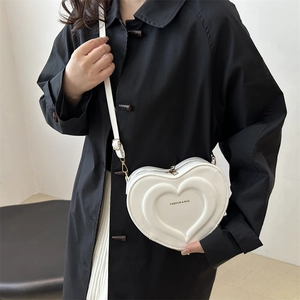 White heart-shaped crossbody bag with quilted pattern and adjustable strap on a model