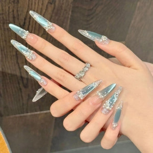 Dettaglio macro di unghie a stiletto blu ghiaccio con perle, strass e decorazioni floreali