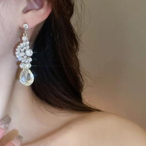 Detailed close-up of a silver drop earring with sparkling rhinestones on a model