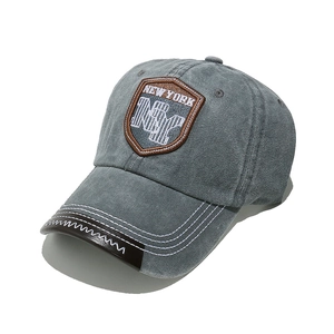 Detailed close-up of retro NY embroidery patch and leather brim on grey washed cotton cap