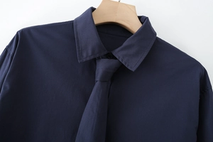 Detail of dark blue cotton poplin shirt with matching tie on wooden hanger