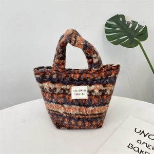 Close-up of fluffy multi-color tweed plush texture and brand label on a small tote bag