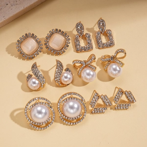 Elegant 6-pair gold earring set with rhinestones and faux pearls on a beige surface
