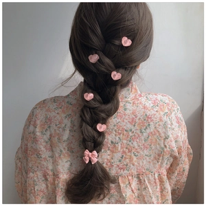 Pink heart hair clips and bow scrunchie styled on a braided hairstyle for women