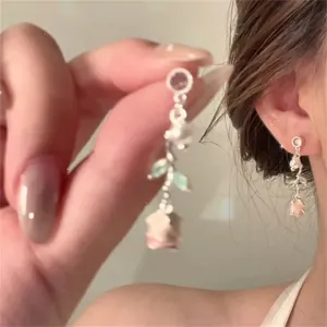 Detailed close-up of pink gradient acrylic flower earrings with faux pearls and green leaves