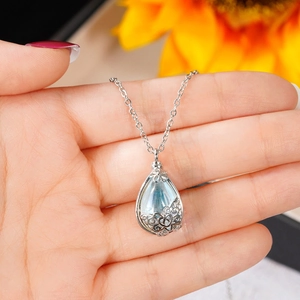 Dettaglio del ciondolo a goccia traforato in argento con pietra blu e motivo a cuore