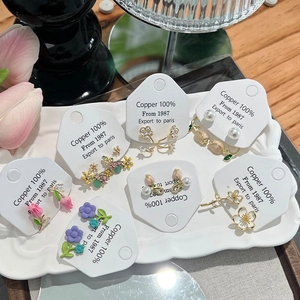 Elegant floral copper earring set with pearls and rhinestones in a white tray