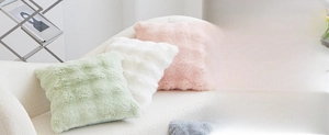Detailed view of square plush pillows in pastel colors on a soft white sofa couch