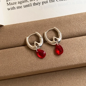 Elegant 18K gold plated hoop earrings with red teardrop gems on a vintage book