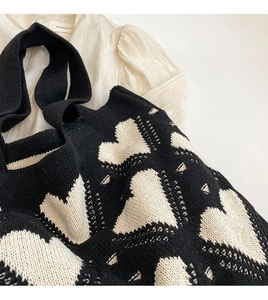 Close-up of the textured knit fabric and white heart pattern on the black tote bag