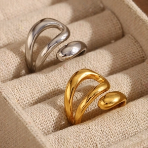 Close-up of elegant triple-layered gold and silver snake rings on a cream fabric surface