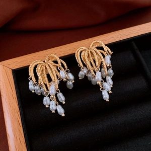 Detail of vintage gold plated earrings with radiating metal lines and small white pearls