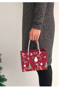 Detailed view of red Christmas paper gift bag with snowman pattern and rope handles