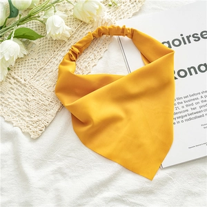 Flat lay of a yellow chiffon headscarf next to lace and white flowers on white fabric