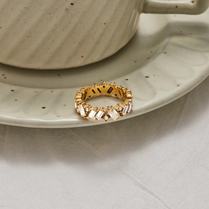 Nahaufnahme eines goldenen Edelstahlrings mit weißen Zirkonias auf Keramikschale