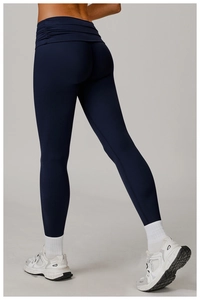 Close-up of dark blue high-waisted yoga pants featuring gathered side pleated waist details