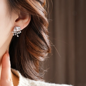 Detail of silver pearl flower earring with zircons worn by model in a close-up shot