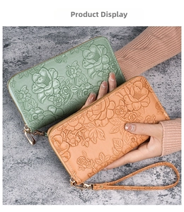 Detail view of a long faux leather wallet with 3D floral embossing and a wristlet strap