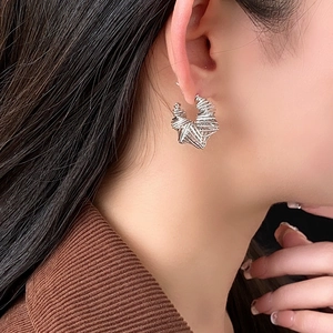 Macro shot of a twisted C-shape silver earring on a model for a stylish metallic look