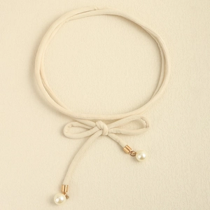 Detail of beige knotted waist rope with gold tips and white pearl drop accents