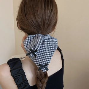 Detail of a black and white checkered bow hair clip on a model's braided hair