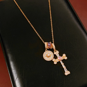 Detailed close-up of 18k gold cross pendant with pink heart zircon and star detail