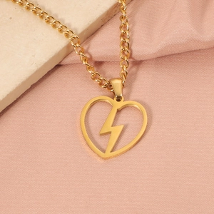 Détail d'un pendentif cœur doré avec éclair sur un fond en soie rose élégant