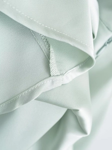 Macro detail of fine stitching and smooth satin texture on a light green dress