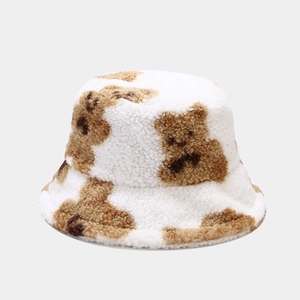 Close-up of soft white faux fur bucket hat featuring a cute brown bear pattern detail