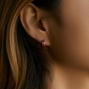 18K gold plated hoop earrings with red zircon stones worn on a model's earlobe