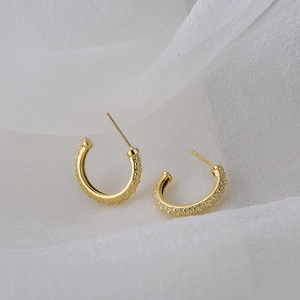 Minimalist 18K gold plated C-shaped earrings with granular bead texture on white fabric