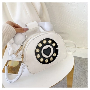 Detailed view of a white vintage telephone bag with rotary dial and heart detail