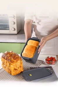 Close-up of a collapsible gray silicone bread mold with lid and fresh toast