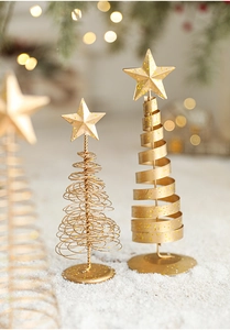 Detailed view of golden iron mini Christmas tree decorations on snow with bokeh lights