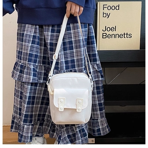 Minimalist white canvas mini crossbody bag shown on model in a cozy vintage setting