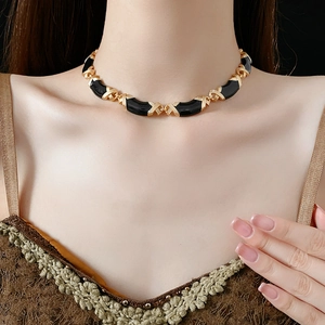 Close-up of black and gold geometric choker necklace shown on model's neck