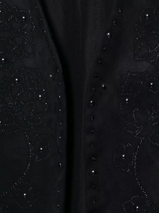 Dettaglio di ricamo floreale e perline nere su gilet con texture scamosciata nera