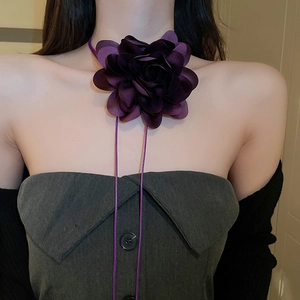 Detail of dark purple fabric flower choker necklace with long ribbon on female model