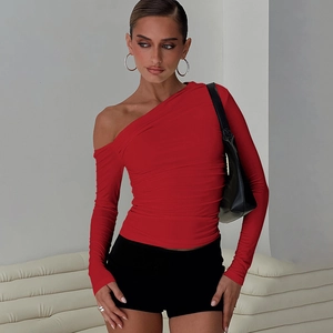 Détail du haut court rouge à une épaule et manches longues en tissu élastique