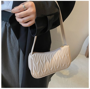 Detail of beige shoulder bag featuring pleated texture and premium metal zipper closure