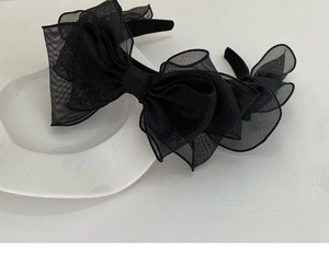 Detail view of a layered black mesh bow headband on a white decorative plate
