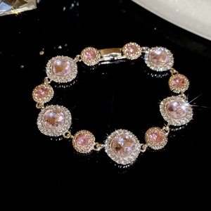 Nahaufnahme eines eleganten Armbands mit rosa Edelsteinen, Goldauflage und Kristallkranz