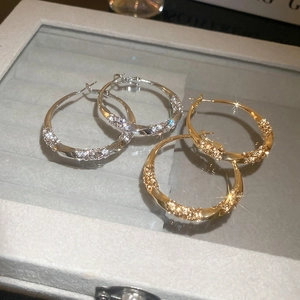 Macro shot of twisted hoop earrings with micro-inlaid zircon in gold and silver finish