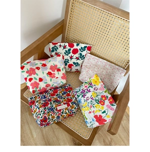 Close-up of five assorted floral fabric makeup bags on a woven rattan chair