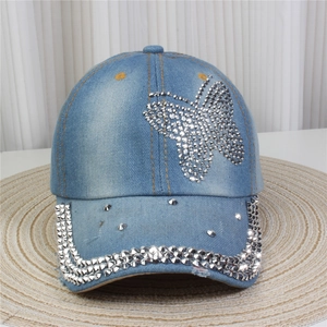 Détail de papillon en strass étincelant et rivets sur une casquette de baseball en jean