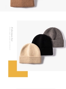 Stacked collection of knitted fisherman hats in beige, black, and grey textured fabrics