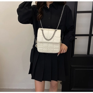 Detailed view of the quilted cream crossbody bag with a metallic silver chain strap