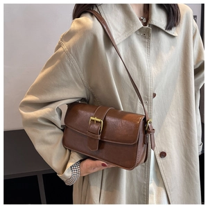Detail of vintage brown shoulder bag with smooth leather texture and gold buckle