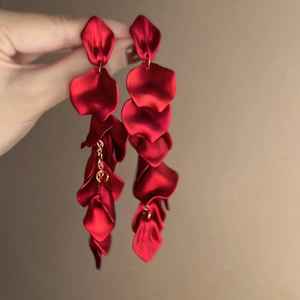 Boucles d'oreilles pétales rouge foncé avec chaînes dorées tenues à la main